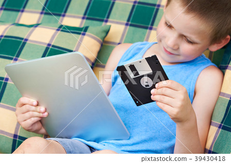 Little boy with floppy disk and tablet pc Little boy with floppy disk and tablet pc 39430418