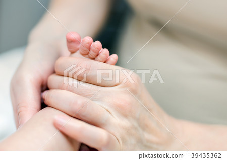 Mother making feet massage for infant baby. Parent 39435362