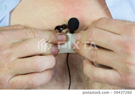 A man attaches a hidden microphone to his chest wi 39437260