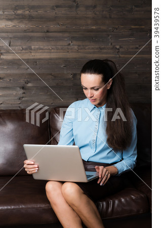 Happy brunette sitting on sofa in living room 39439578