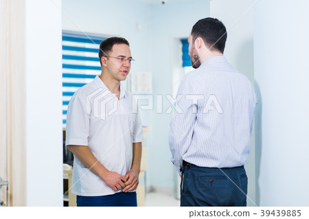 Doctor talking to a patient in a hallway Doctor talking to a patient in a hallway 39439885