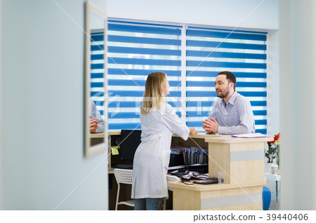 Nurse and patient conversing at reception desk in 39440406