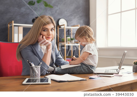 Young mother holding baby while writing notes 39443030