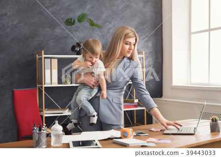 Young mother holding baby while using laptop 39443033