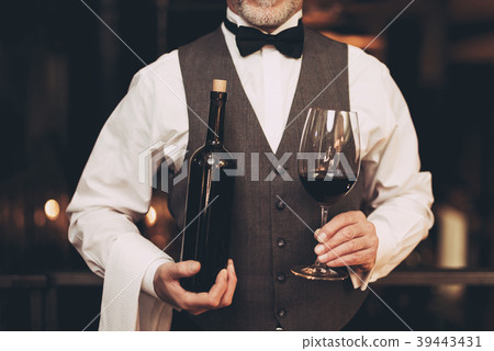 Experienced sommelier standing with bottle of wine 39443431