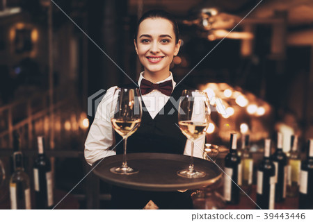 Joyful waitress holds tray with glasses Joyful waitress holds tray with glasses 39443446