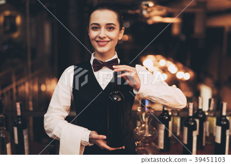 Joyful elegant waitress holding bottle Joyful elegant waitress holding bottle 39451103