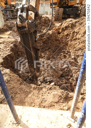 Excavator with a jackhammer breaks rocks in the 39470842