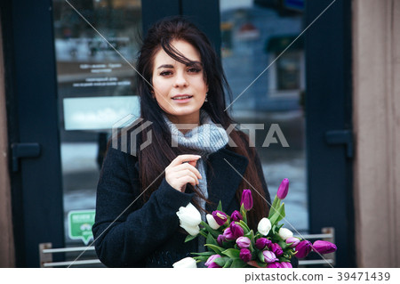 Happy woman holding spring flowers outdoor in city 39471439