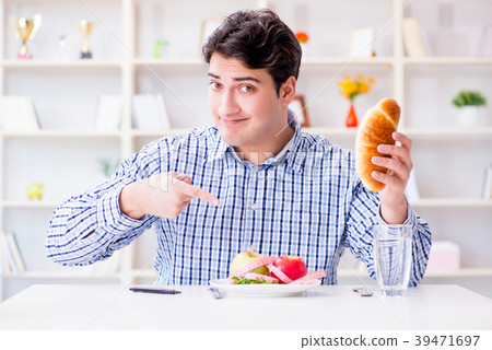 Man having dilemma between healthy food and bread Man having dilemma between healthy food and bread 39471697