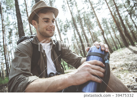 Optimistic hiker is holding vacuum flask in forest 39475332