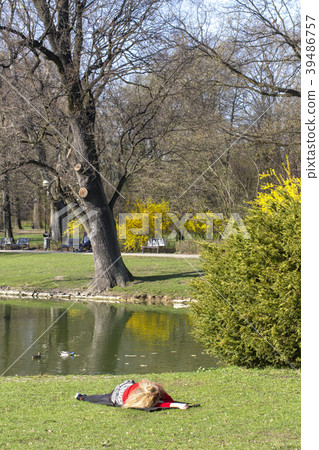young woman laying in a meadow in front of a lake 39486757