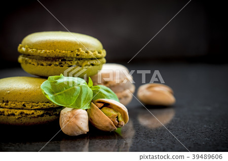 two pistachio macarons with nuts on dark 39489606