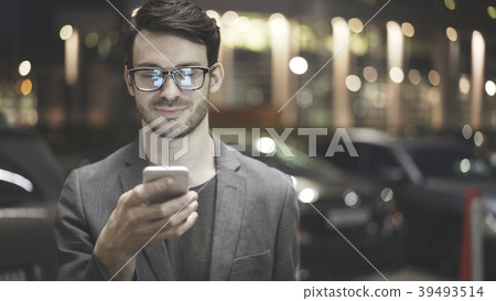 A smiling man is holding and looking at his A smiling man is holding and looking at his 39493514