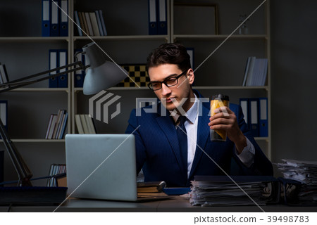 Employee working late and drinking strong coffee Employee working late and drinking strong coffee 39498783