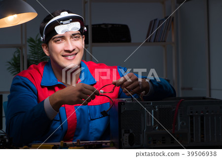 Computer specialist repairing PC late at night 39506938