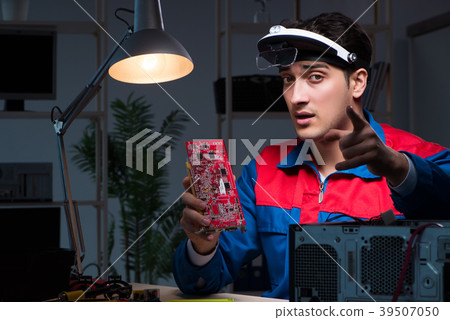 Computer specialist repairing PC late at night 39507050