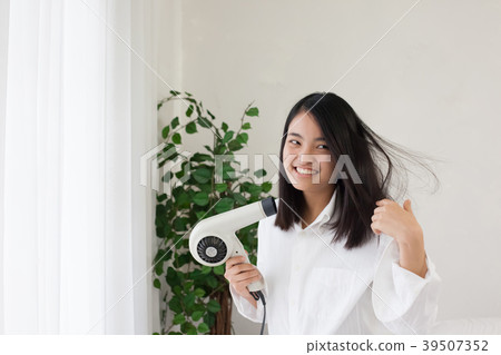 烘乾她的頭髮的婦女在臥室 烘乾她的頭髮的婦女在臥室 39507352