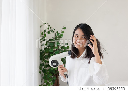 烘乾她的頭髮的婦女在臥室 烘乾她的頭髮的婦女在臥室 39507353
