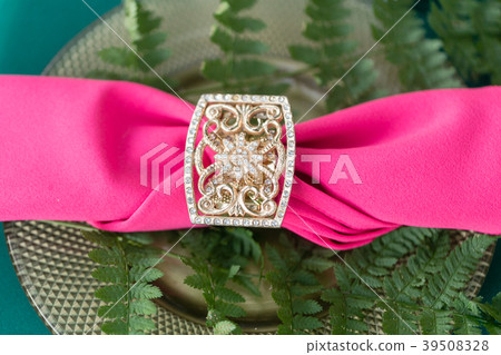 Pink napkin with a patterned clip. table setting Pink napkin with a patterned clip. table setting 39508328