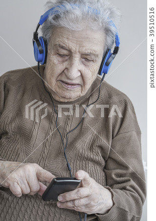 Senior woman listening music with headphones Senior woman listening music with headphones 39510516