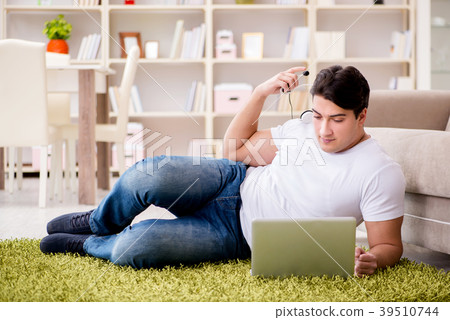 Man working on laptop at home on carpet floor 39510744