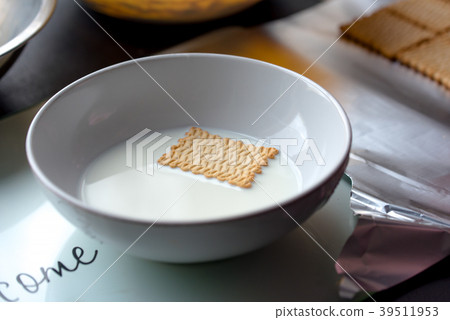 Biscuit dipped in bowl filled with milk  39511953