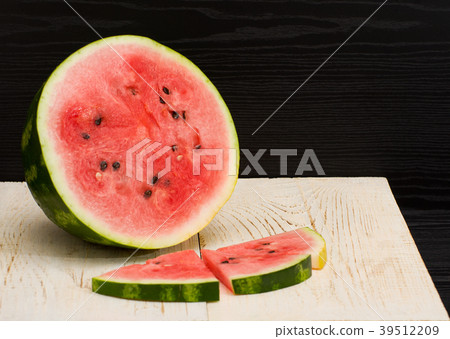 Half cut watermelon and slices on a wooden table 39512209