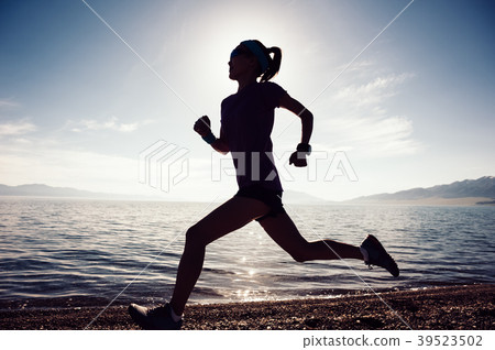 Young  sporty woman running on rocky seaside 39523502
