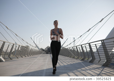 Active woman runner jogging across bridge Active woman runner jogging across bridge 39525825