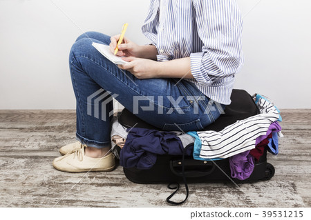 Young girl casually packs black suitcase Young girl casually packs black suitcase 39531215