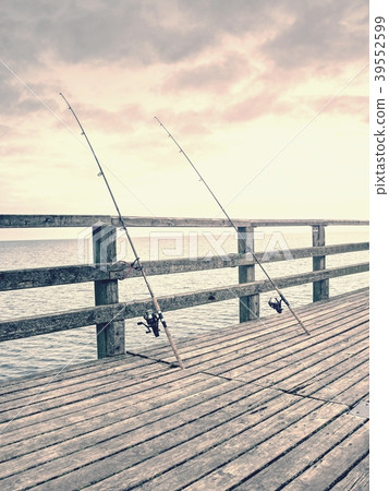 Several fishing rods against the wooden railing  39552599