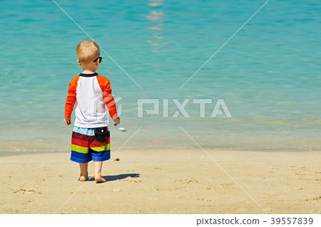Two year old toddler boy walking on beach 39557839