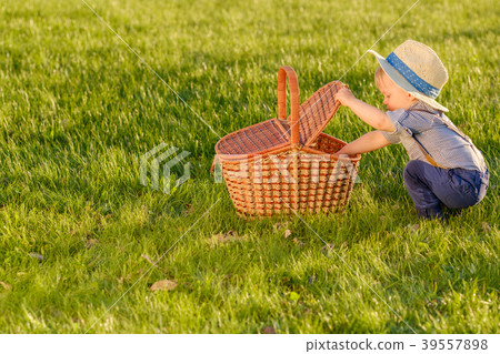 Toddler child outdoors. One year old baby boy wearing straw hat looking in picnic basket Toddler child outdoors. One year old baby boy wearing straw hat looking in picnic basket 39557898