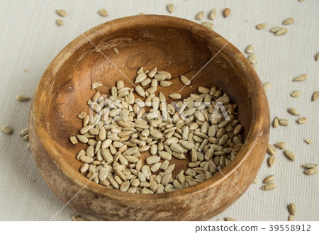 Peeled sunflower seeds in old wooden bowl on white Peeled sunflower seeds in old wooden bowl on white 39558912