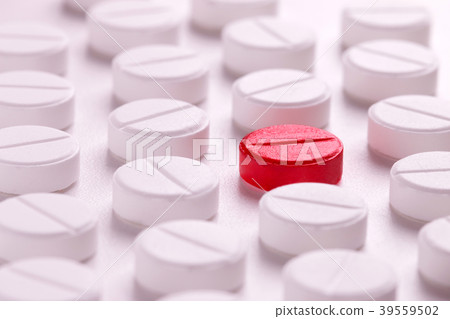 A lot of white pills around one red. 39559502