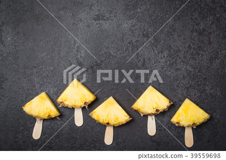 Ripe Pineapple slices on sticks on a black Ripe Pineapple slices on sticks on a black 39559698