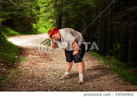 Overweight woman tired after a run in the forest Overweight woman tired after a run in the forest 39560902