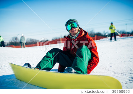 Snowboarder in glasses sitting on snowy slope Snowboarder in glasses sitting on snowy slope 39560993