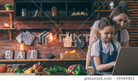 Mother and daughter with laptop cooking Mother and daughter with laptop cooking 39564861