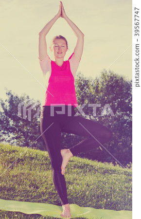 Female 26-32 years old is staying and doing meditation in pink T-shirt Female 26-32 years old is staying and doing meditation in pink T-shirt 39567747
