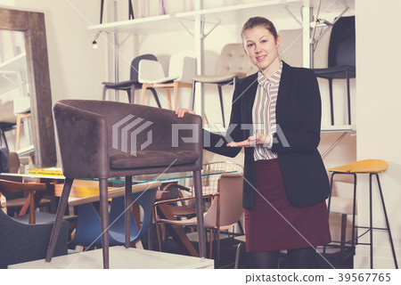 Saleswoman suggesting armchair in furniture salon 39567765