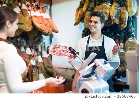 Seller offering jamon to customer. Seller offering jamon to customer. 39568466
