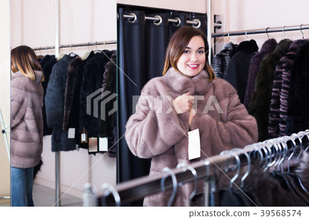 Nice girl customer trying on new fur coat Nice girl customer trying on new fur coat 39568574