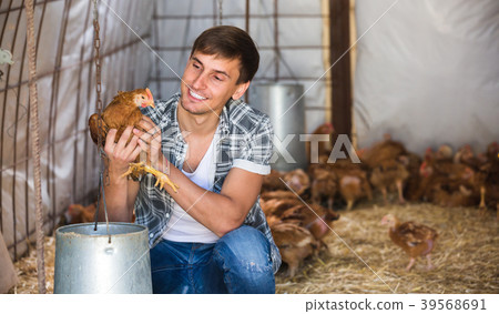 Smiling countryman holding brown chicken 39568691