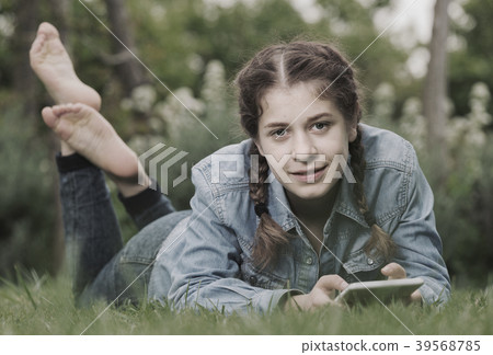 young girl using digital tablet while lying in green spring garden young girl using digital tablet while lying in green spring garden 39568785