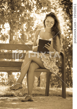 Girl on bench in park with ereader Girl on bench in park with ereader 39568911