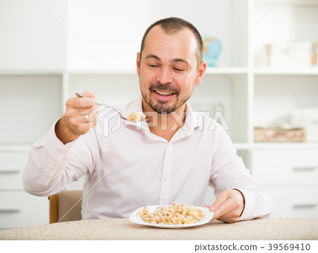 Positive young man eating porridge 39569410