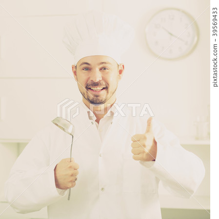 Positive young cook holding soup ladle 39569433