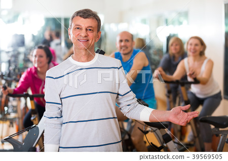 Elderly man on fitness cycle in fitness club. Elderly man on fitness cycle in fitness club. 39569505